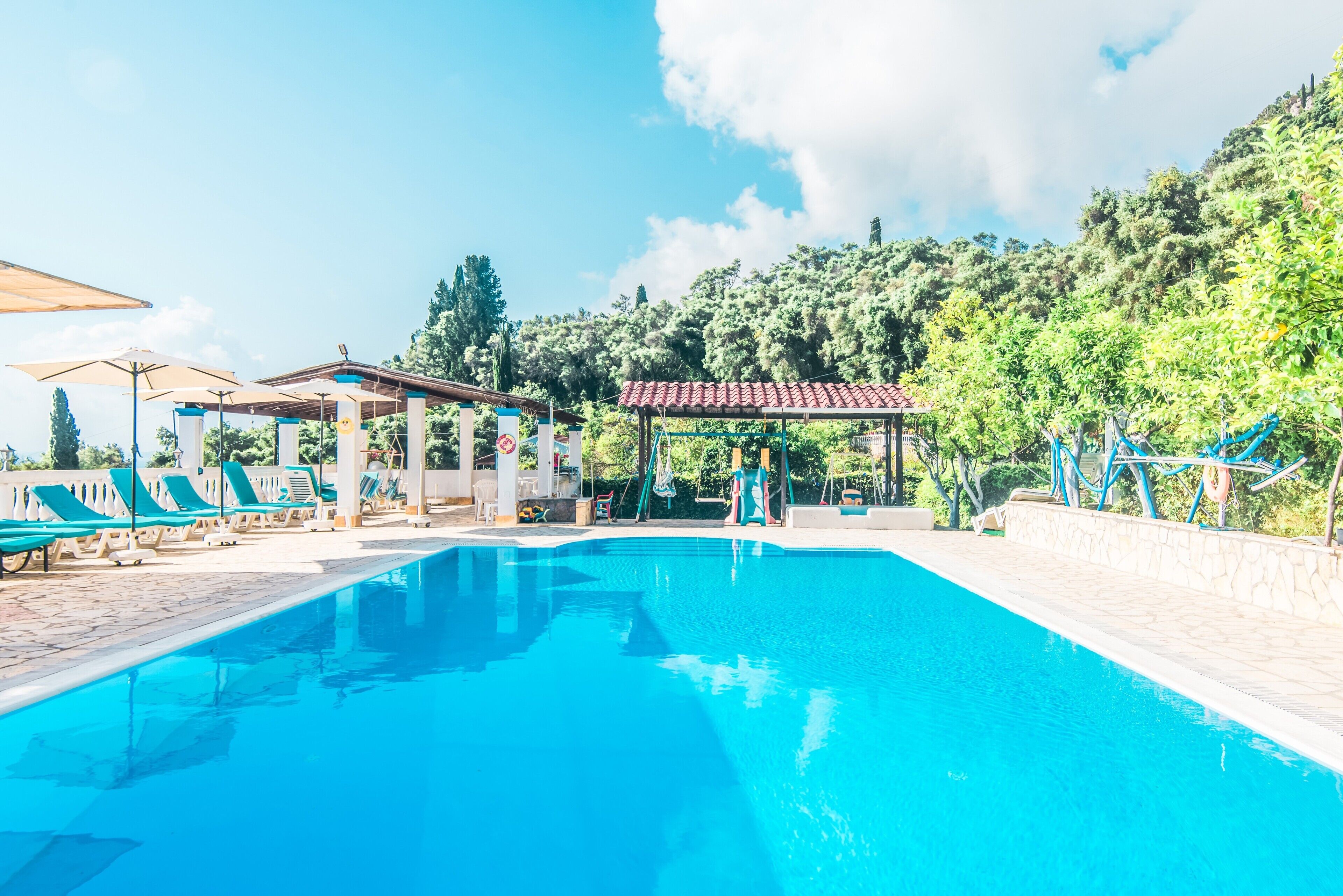 Una piscina con lettini e un gazebo.