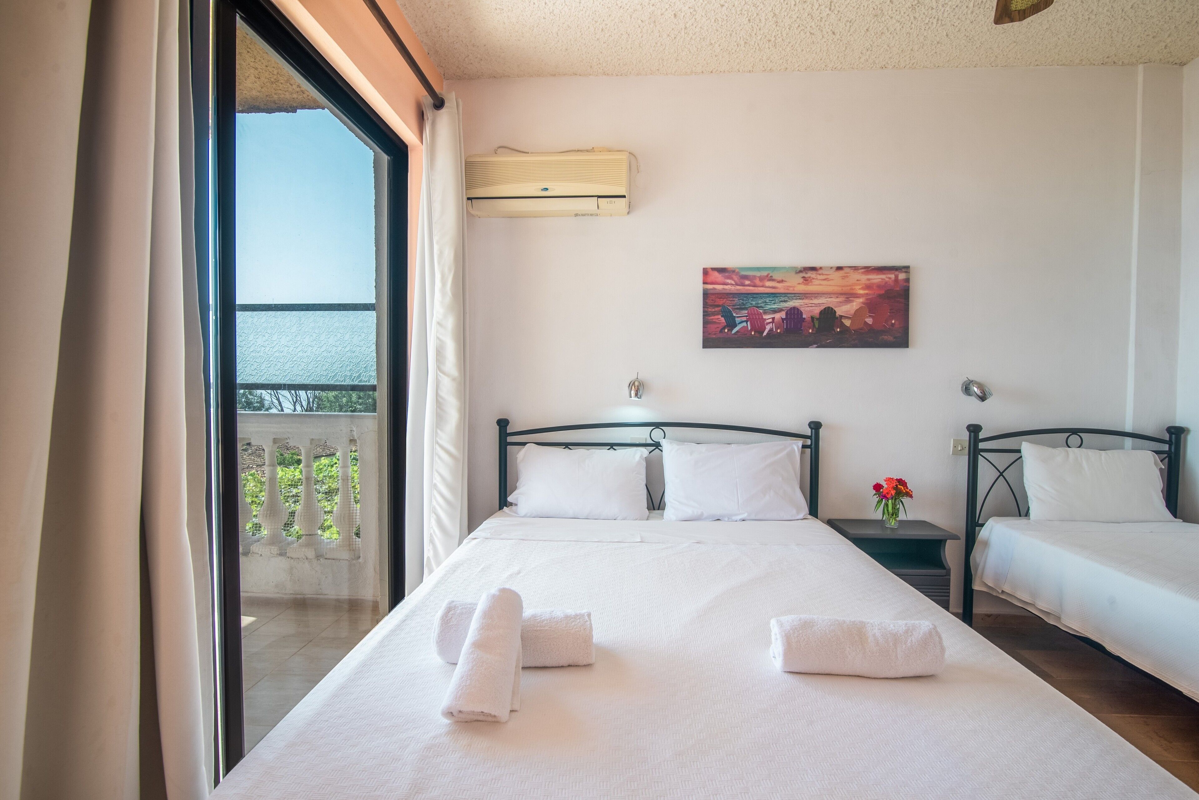 Una camera d'albergo con un'ampia finestra, un quadro appeso alla parete e due letti con asciugamani.