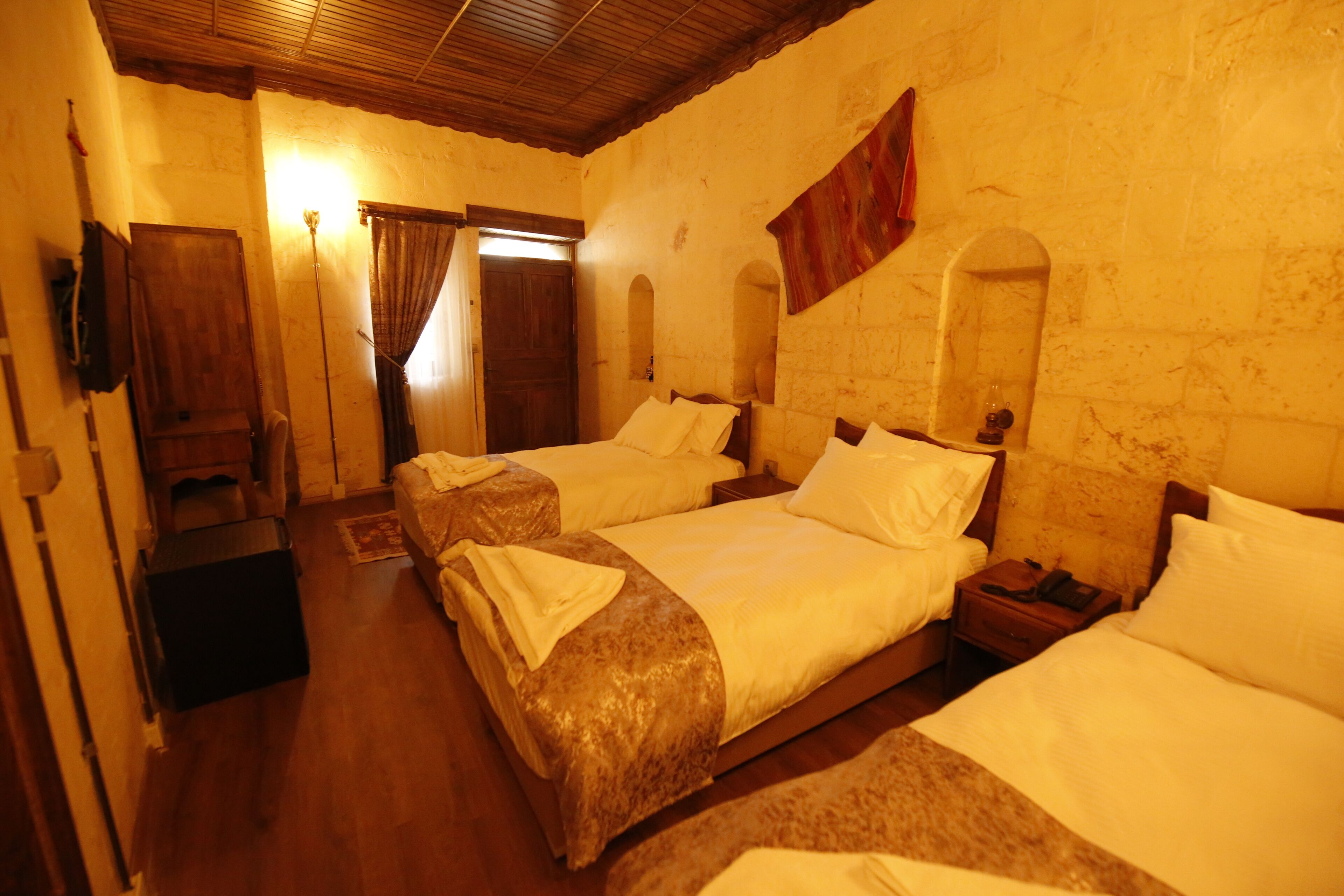 Ein Hotelzimmer mit zwei Betten, Holzboden, Holzboden und einer Ziegelwand.
