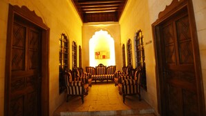 A corridor with wooden doors and chairs arranged in a semi-circle. - Kaliruha Butik Otel (Sanliurfa)