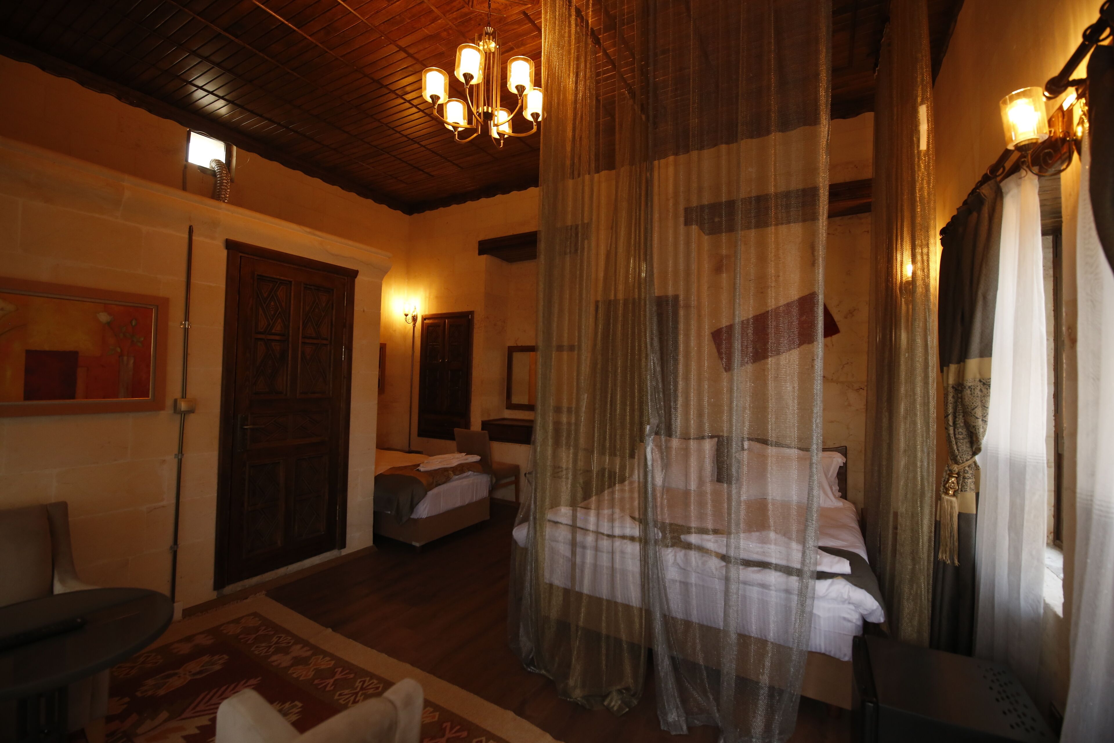 A room with a bed, a chair, a table, and a window with curtains.