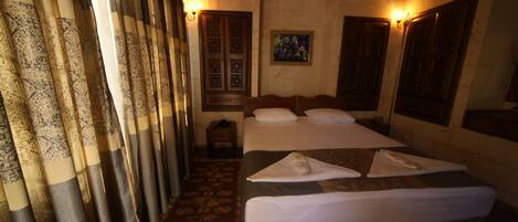 A hotel room with a bed, curtains, a painting, and a small table.