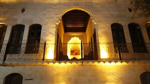 A historic building with a central arched entrance, ornate iron railings, and a stone facade. - Kaliruha Butik Otel (Sanliurfa)