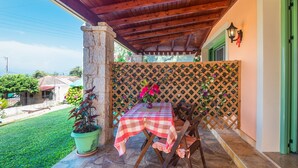 A covered patio with a table and chairs, a potted plant, and a lattice wall.