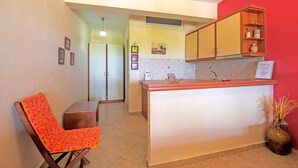 A compact kitchen with a central island, a dining area with a chair, and a red accent wall.