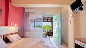 A bedroom with a bed, a bedside lamp, a TV, and a view of the outside.