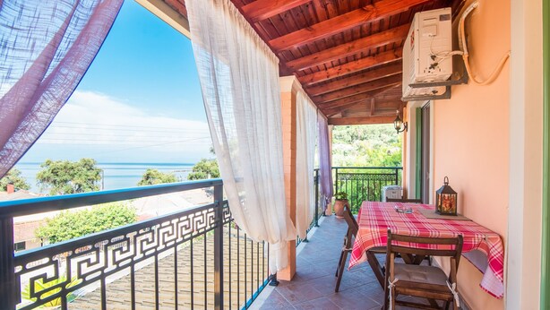 A balcony with a table and chairs, a view of the sea, and a power outlet on the wall. - 'Villa Pepy Apartment' with Sea View, Garden & Wi-Fi (Corfu)