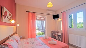 A bedroom with a bed, a desk, a chair, a TV, and a balcony with a view. - 'Villa Pepy Apartment' with Sea View, Garden & Wi-Fi (Corfu)