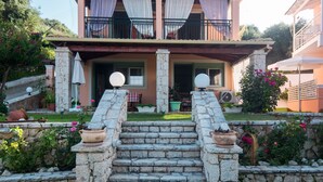 A stone staircase leading to a house with a balcony, surrounded by greenery and potted plants. - 'Villa Pepy Apartment' with Sea View, Garden & Wi-Fi (Corfu)