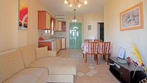 A living room with a sofa, dining table, chairs, a chandelier, and artwork on the walls. - 'Villa Pepy Luxury Apartment' with Mountain View, Garden & Wi-Fi (Corfu)