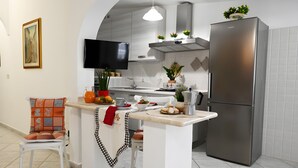 Une cuisine moderne dotée d’un îlot central intégré, d’appareils électroménagers en acier inoxydable et d’un téléviseur à écran plat.