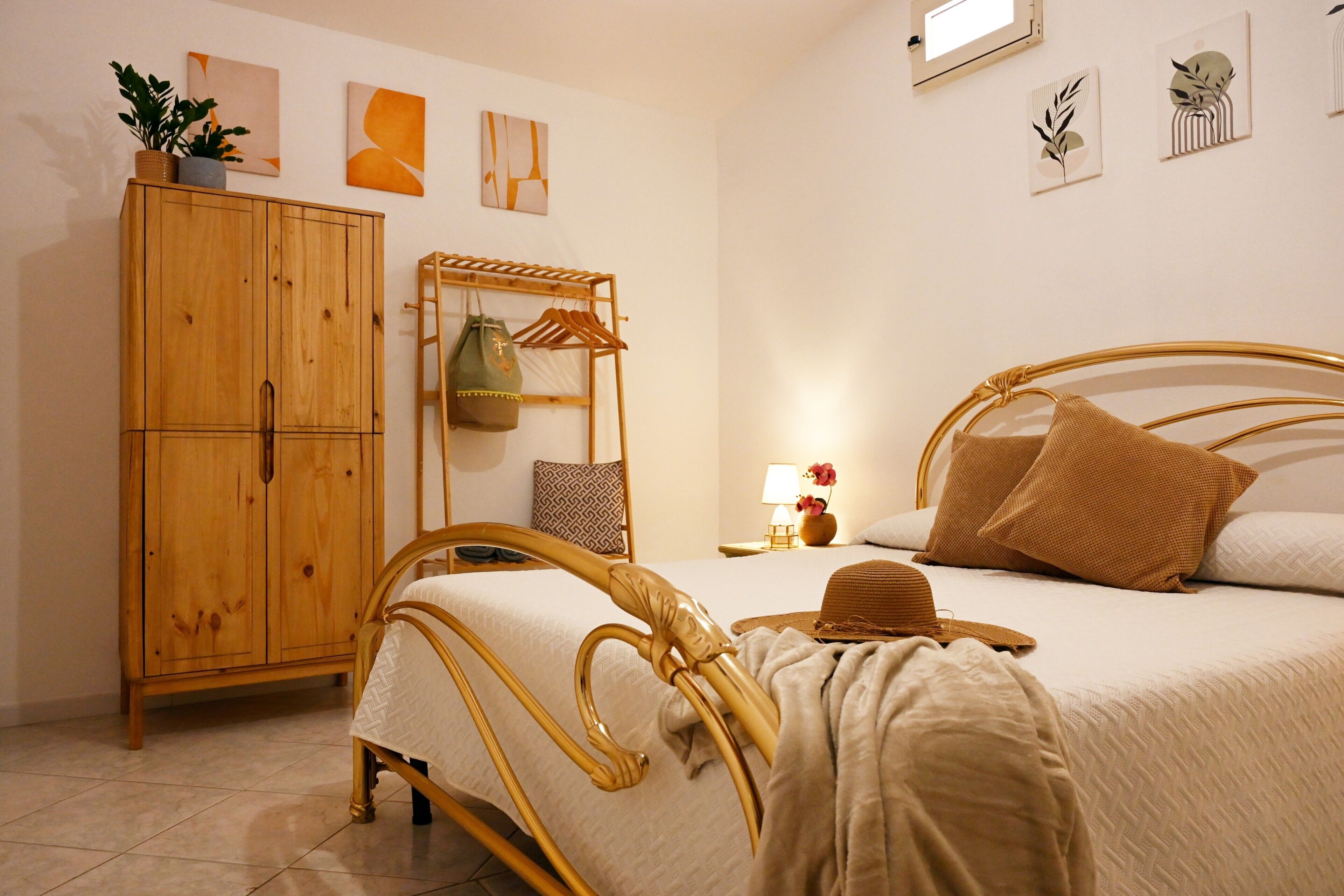 Una camera da letto con un'armadio in legno, un letto con testiera, un comodino con lampada e decorazioni alle pareti.