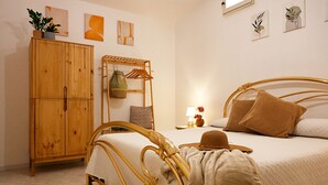 Une chambre avec une armoire en bois, un lit avec une tête de lit, une table de chevet avec une lampe et des œuvres d’art murales.