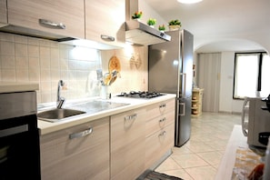 A modern kitchen with a gas stove, stainless steel appliances, and light wood cabinetry.