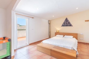 A bedroom with a bed, a green baby gate, and a view through a sliding door.