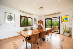 A dining area with a wooden table, brown chairs, and a vase of flowers.