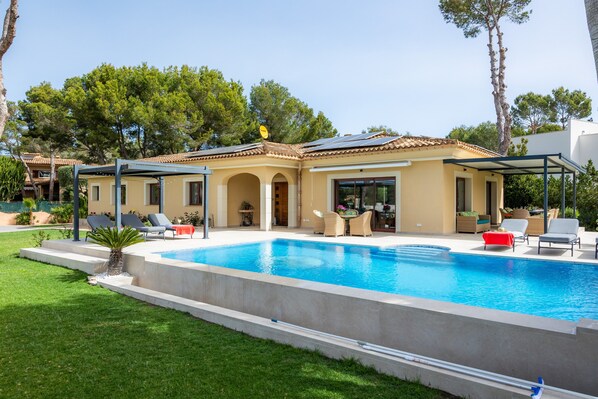Una casa con piscina, mobili da esterno e patio coperto.