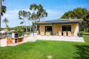 Una casa con patio, mobili da esterno e un'area barbecue.