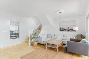 A modern living room with a staircase, a sofa, a coffee table, and a lamp.