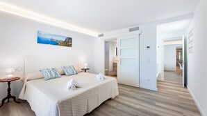 A hotel room with a bed, a nightstand, a painting, and a bathroom door. - Apartment 'Albercutx Pollentia 2' with Wi-Fi and Air Conditioning (Puerto Pollensa)