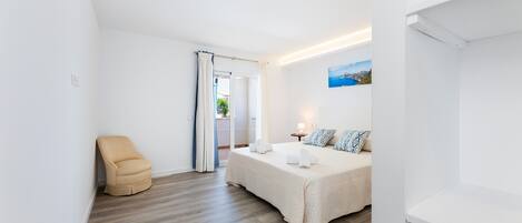 A bedroom with a bed, a chair, a nightstand, a lamp, and a painting on the wall.