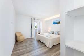 Une chambre à coucher avec un lit, une chaise, une table de chevet, une lampe et un tableau au mur.