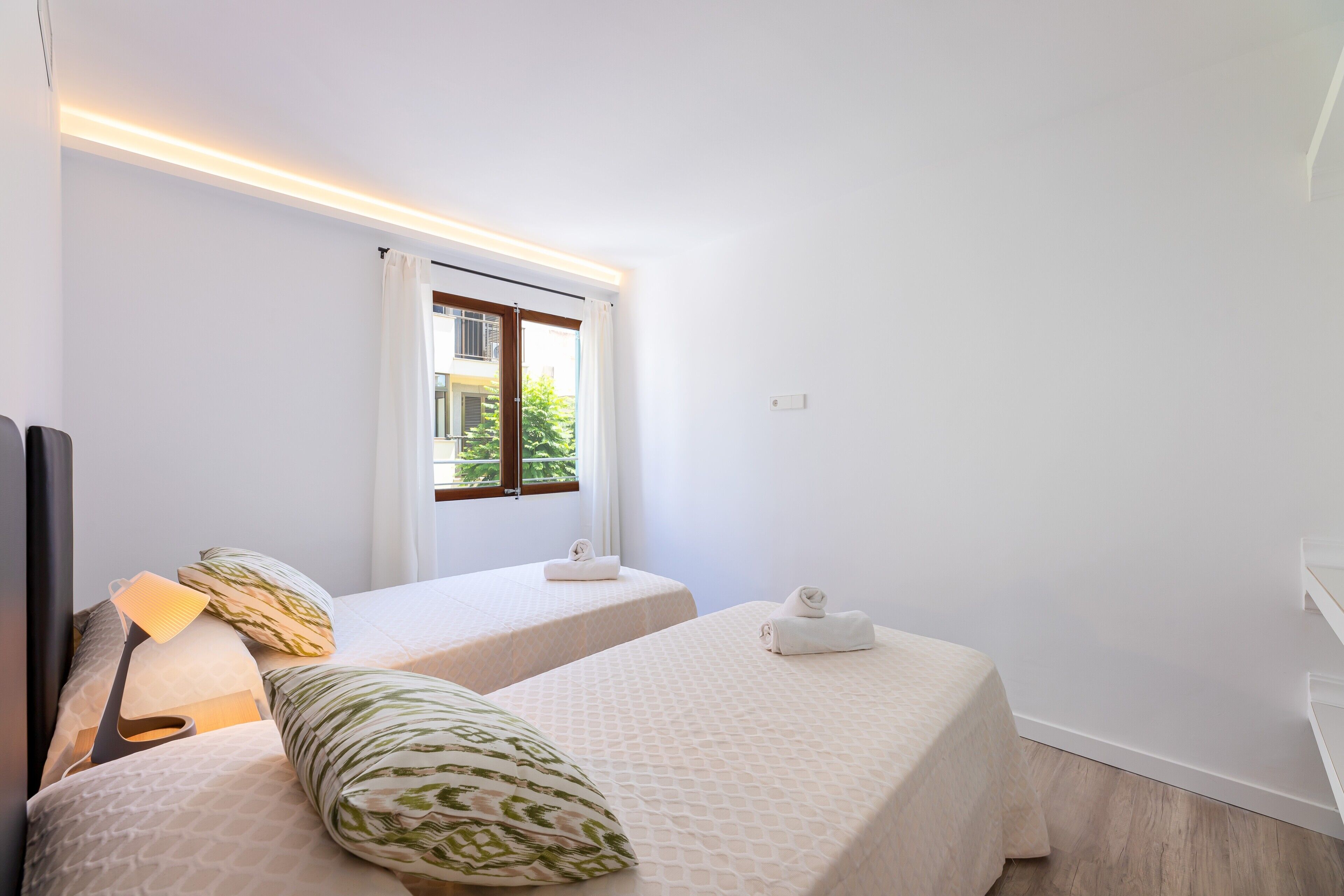 Una habitación de hotel con dos camas, una ventana y una mesita de noche con lámpara.