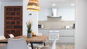 A modern kitchen with white cabinets, a wooden dining table, and a hanging light fixture. - Apartment 'Albercutx Pollentia 2' with Wi-Fi and Air Conditioning (Puerto Pollensa)