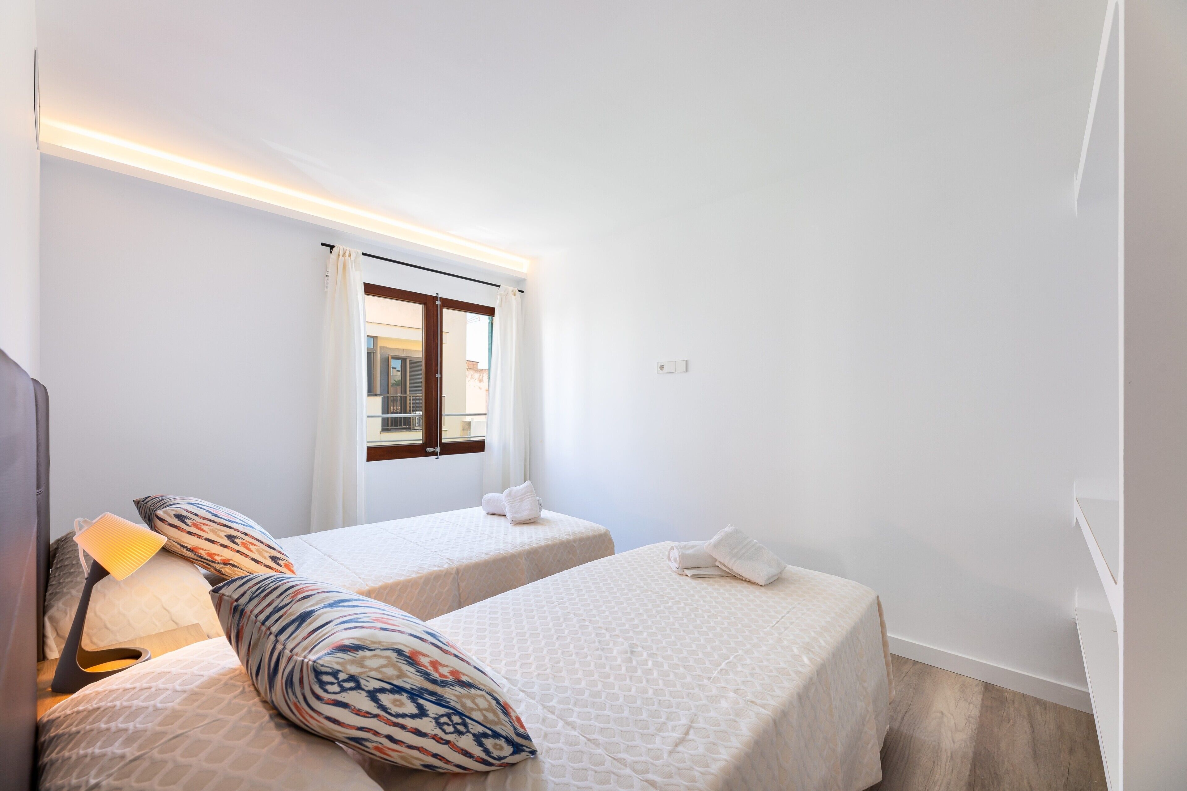 Une chambre d’hôtel avec deux lits, une fenêtre avec des rideaux, une lampe et une vue sur l’extérieur.