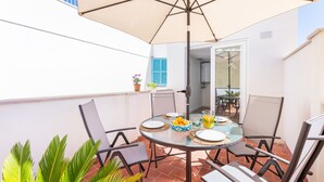 A round table with chairs, a large umbrella, and a bowl of fruit. - Holiday Apartment 'Albercutx Pollentia 3' Near the Beach with Private Terrace (Pollensa)
