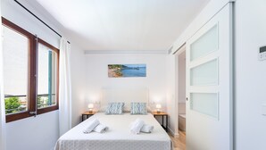 A hotel room with a bed, two bedside tables, a painting, and a view of the sea. - Holiday Apartment 'Albercutx Pollentia 3' Near the Beach with Private Terrace (Pollensa)
