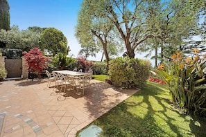 A patio with a table and chairs, surrounded by greenery and trees.