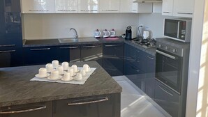 A modern kitchen with a central island, stainless steel appliances, and a chandelier.