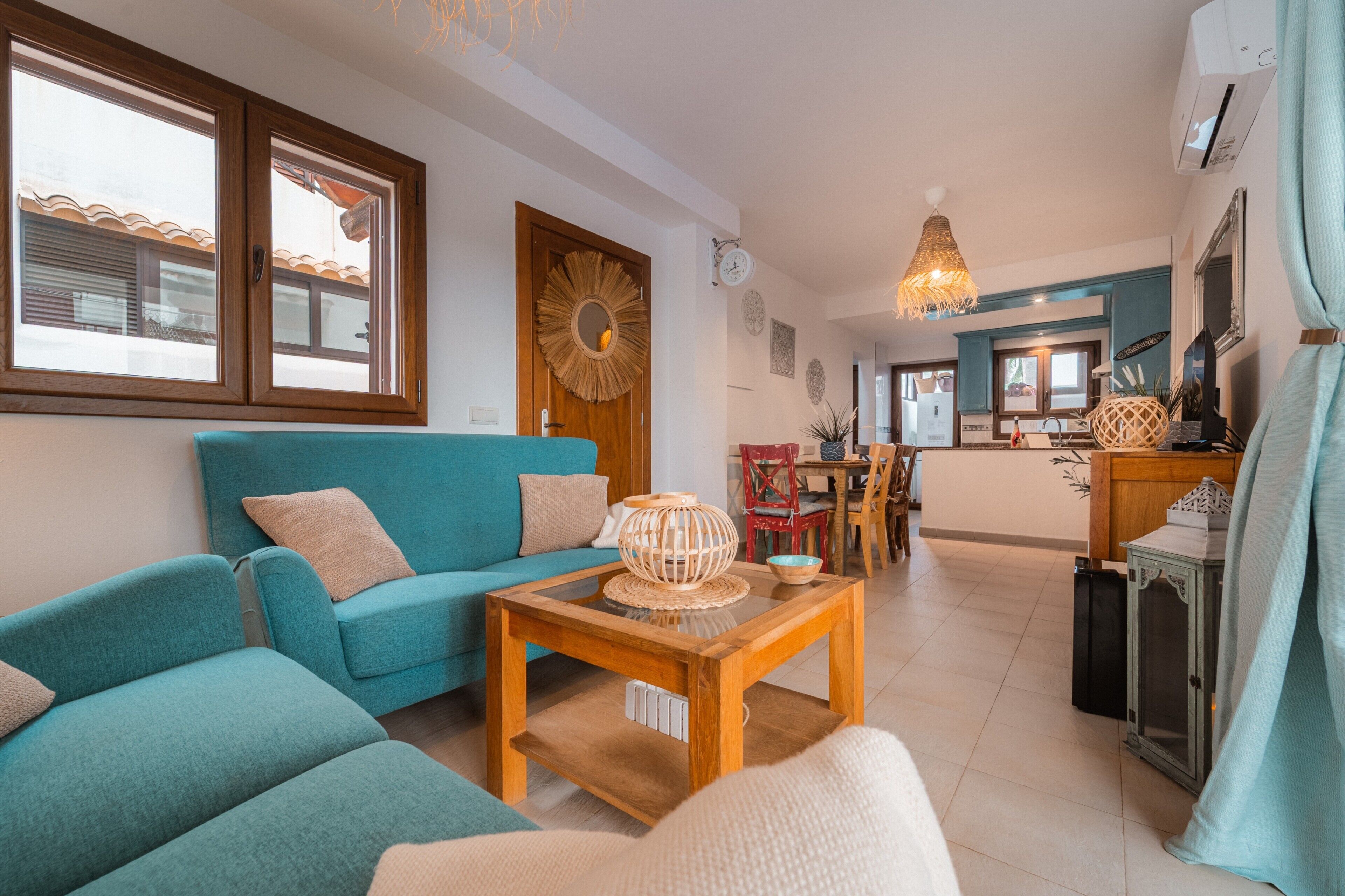 A living room with a blue sofa, a wooden coffee table, and a dining area in the background.