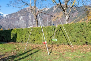 Spielplatz mit Schaukeln vor einer Bergkulisse.