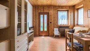 A wooden-paneled room with a door, a chair, a table, and a window. - Appartamento Adamello Casa Lucia – Mountain View, Garden, Parking (Pinzolo)
