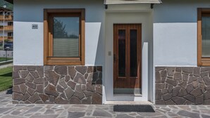 A building with a stone facade, a wooden door, and a window with blinds. - Appartamento Adamello Casa Lucia – Mountain View, Garden, Parking (Pinzolo)