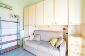 A room with a sofa, a metal shelf unit, and a cabinet with drawers. - Apartment "Casa di Alice" with Sea View, Balcony and Wi-Fi (Siracusa)