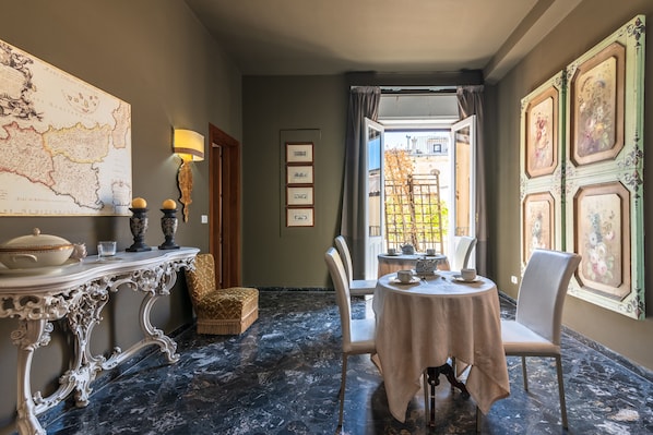 A dining area with a marble floor, a table set for two, and a map on the wall.