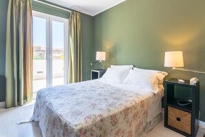 A hotel room with a bed, two bedside tables, a lamp, a small basket, and a view through a sliding door. - Holiday Home 'Casa Neathon' with Wi-Fi, Terrace & Balcony (Noto)