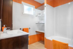 A modern bathroom with a white sink, a glass shower enclosure, and a wooden vanity.