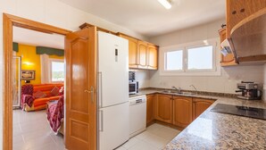 A compact kitchen with wooden cabinets, a built-in microwave, and a stove. - Holiday Home 'Villa Lilia' with Sea View, Private Pool and Wi-Fi (Vilanova i la Geltrú)