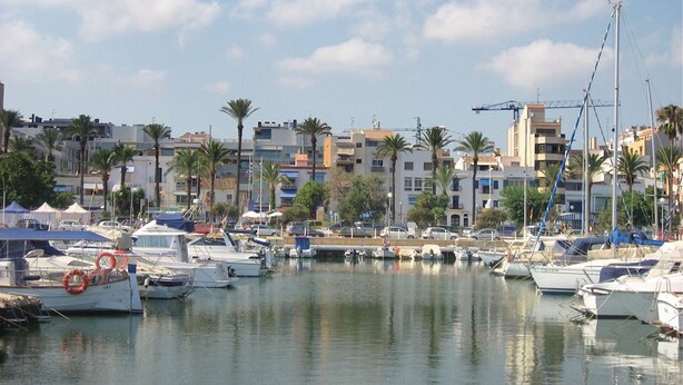 A marina with boats docked, buildings in the background, and palm trees. - Holiday Home 'Villa Lilia' with Sea View, Private Pool and Wi-Fi (Vilanova i la Geltrú)