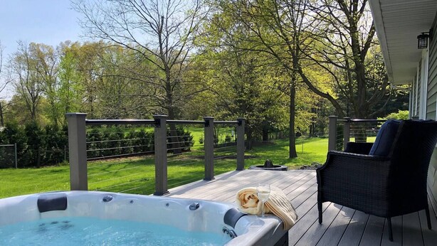 A hot tub on a wooden deck with a chair and a blanket.