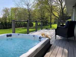 Een hottub op een houten terras met een stoel en een plaid.