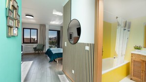 A modern hotel room with a bed, a balcony with a view, a bathroom with a bathtub, and a large mirror.