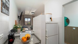 A compact kitchen with a refrigerator, a toaster, a sink, and a window with a view.