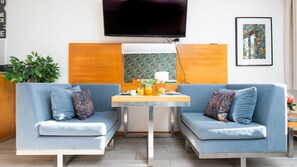 Uma sala de estar moderna com dois sofás azuis, uma mesa de centro, uma televisão de tela plana e uma planta.