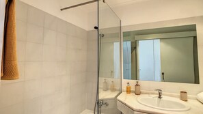 Une salle de bain avec une douche à parois de verre, un lavabo et un miroir.