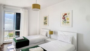 A hotel room with two beds, a balcony with a view, and two framed botanical prints on the wall. - Lido Life Apartment by LovelyStay (Funchal)